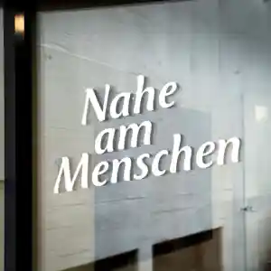 Der Claim Nahe am Menschen steht auf einer Glastür am Eingang der Schule geschrieben